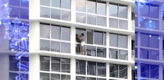 Mujer se pone en peligro al limpiar ventanas de edificio