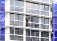 Mujer se pone en peligro al limpiar ventanas de edificio